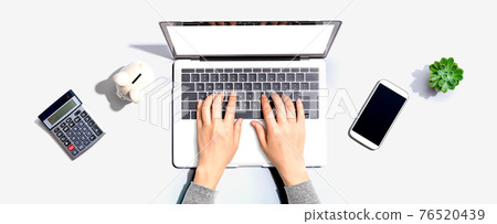 Woman using a laptop computer with a piggy bank Woman using a laptop computer with a piggy bank 76520439