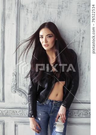 young brunette woman in leather jacket at vintage wall 76522534