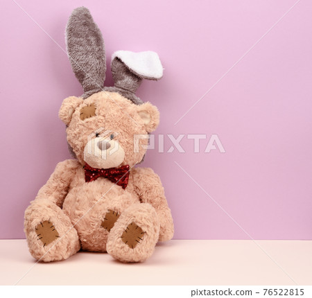 cute brown teddy bear wearing a rabbit mask with long ears on his head cute brown teddy bear wearing a rabbit mask with long ears on his head 76522815