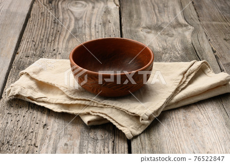 empty brown plate and linen towel on table from old wooden boards empty brown plate and linen towel on table from old wooden boards 76522847