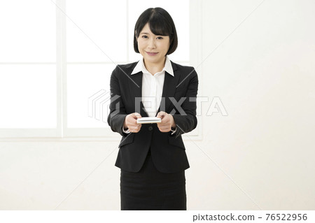 Young woman presenting a business card in a suit (front) Young woman presenting a business card in a suit (front) 76522956