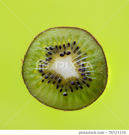 Freshly sliced kiwi fruit on green background close-up. Concept of diet and natural vitamins Freshly sliced kiwi fruit on green background close-up. Concept of diet and natural vitamins 76523138