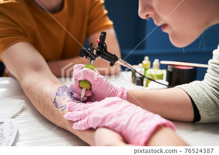 Woman making tattoo for her boyfriend at home with a rotary tattoo machine Woman making tattoo for her boyfriend at home with a rotary tattoo machine 76524387