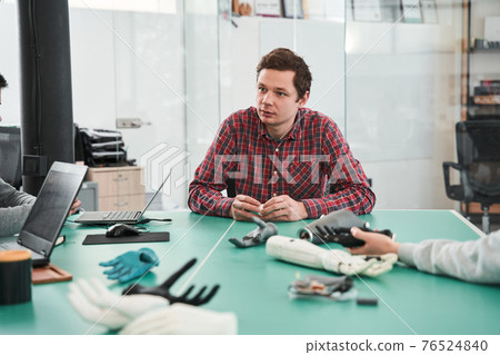 Prosthetist sitting at the table and making presentation about prosthetic hand 76524840