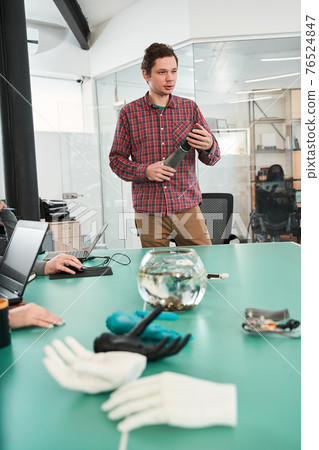 Prosthetist holding prosthetic hand and making presentation of it 76524847