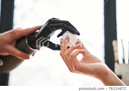 Engineer passes a tennis ball with the bionic prosthesis hand to his colleague 76524872