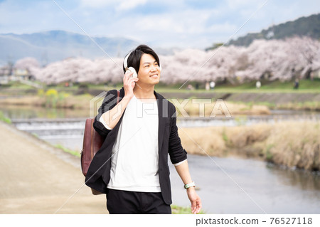 A man enjoying a walk while listening to music 76527118