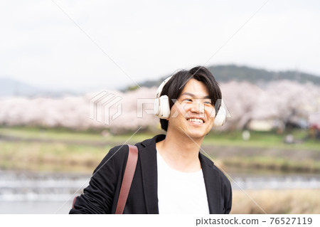 A man enjoying a walk while listening to music 76527119