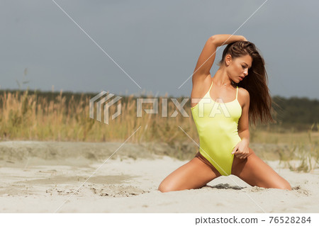Alluring model in yellow swimsuit on sandy shore Alluring model in yellow swimsuit on sandy shore 76528284