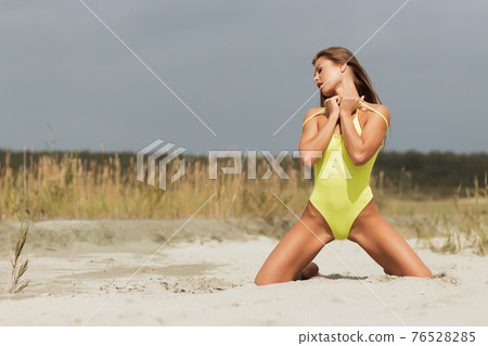 Alluring model in yellow swimsuit on sandy shore Alluring model in yellow swimsuit on sandy shore 76528285