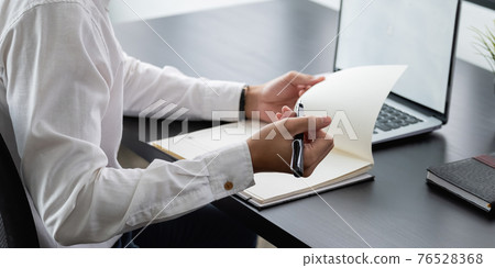 Business planning, business man writing on notebook and working on laptop computer in modern office. Man studying online course via laptop and lecture on notepad 76528368