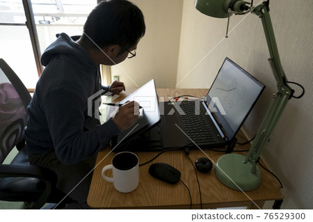 A man drawing an illustration with a pen tab 76529300