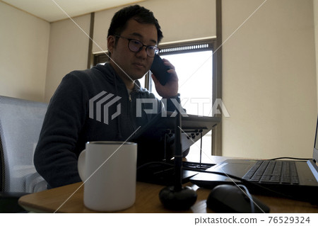 A man drawing an illustration with a pen tab 76529324