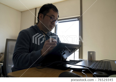 A man drawing an illustration with a pen tab 76529345