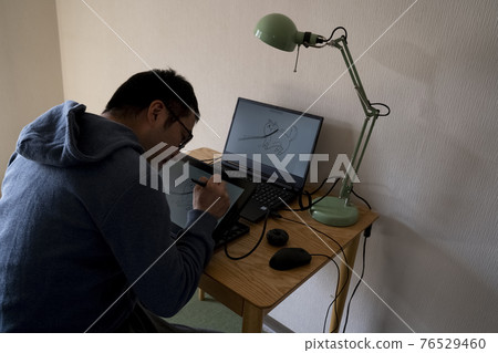 A man drawing an illustration with a pen tab 76529460