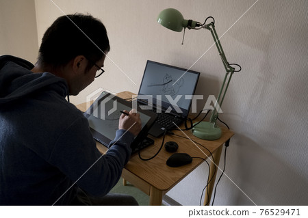A man drawing an illustration with a pen tab 76529471
