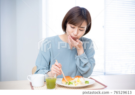一個女人在陽光明媚的桌子上吃早餐 76529613