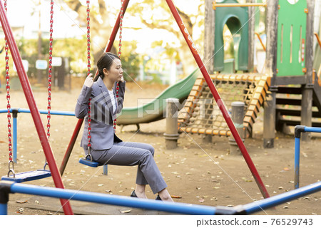 一位年輕女子的西裝暮色在公園裡 一位年輕女子的西裝暮色在公園裡 76529743