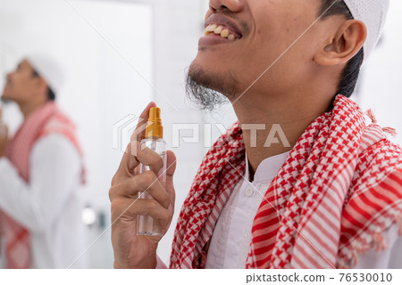 muslim man get dressed and applying perfume to his body 76530010