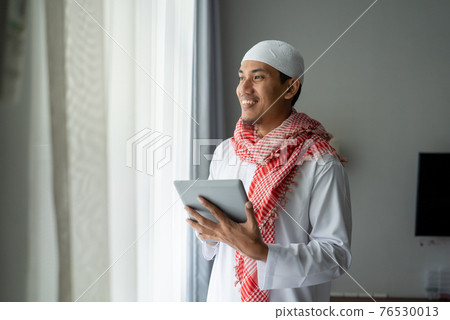 muslim businessman smiling while using tablet pc 76530013