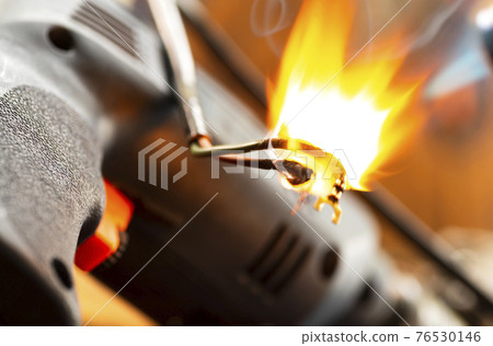 Burning wires on parts of an electrical appliance in a repair shop. Power tool repair Burning wires on parts of an electrical appliance in a repair shop. Power tool repair 76530146