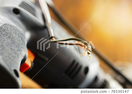 Broken wires from an electrical appliance in a repair shop. Power tool repair Broken wires from an electrical appliance in a repair shop. Power tool repair 76530147