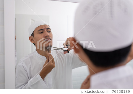muslim asian man unsure to shave off his beard 76530189