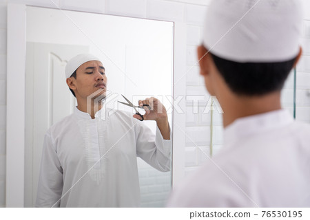muslim asian man unsure to shave off his beard 76530195