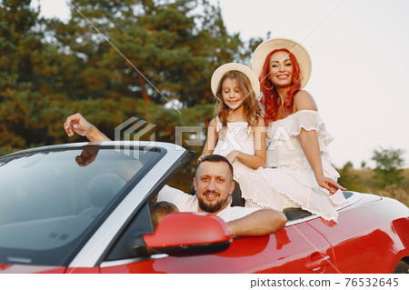 Family in a cabriolet convertible car at the sunset 76532645