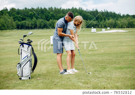 Beautiful couple playing golf on a golf course Beautiful couple playing golf on a golf course 76532812