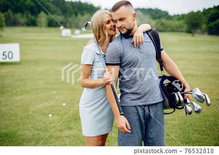 Beautiful couple playing golf on a golf course 76532818