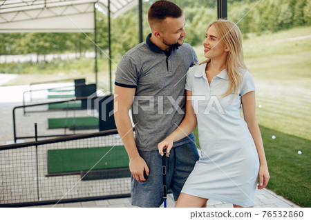 Beautiful couple playing golf on a golf course Beautiful couple playing golf on a golf course 76532860