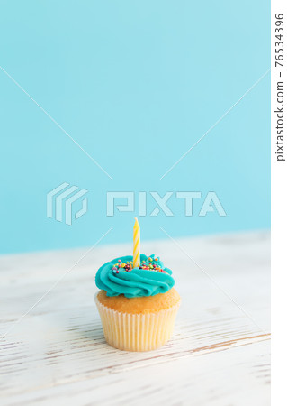 Birthday greeting concept. Yellow candle on muffin, cupcake. Blue background 76534396