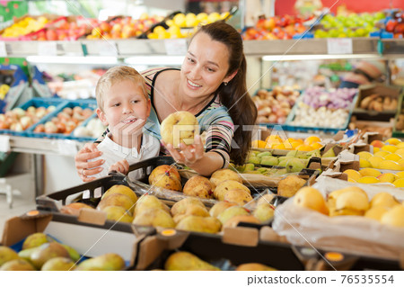 Smiling boy with his mother choosing fruits 76535554