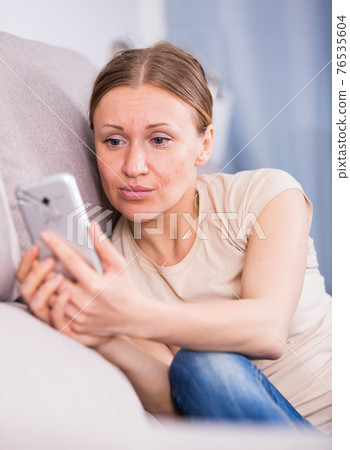 Upset woman with phone 76535604