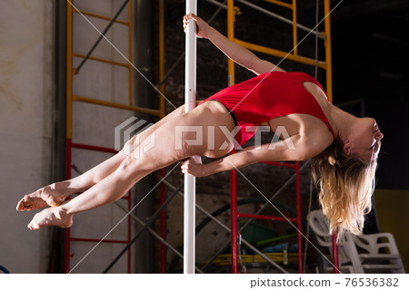 Sexy girl in red swimsuit performs a dance with a pylon 76536382