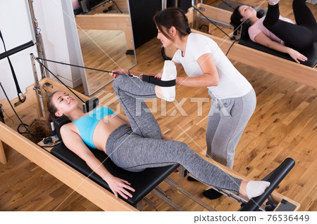 Female pilates trainer helping pilates woman during training 76536449