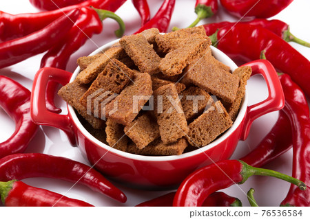 in a red pan, croutons with spices, surrounded by shots of red peppers, spicy snack, concept 76536584