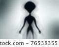 Silhouette of spooky alien and bright light on behind him 76538355