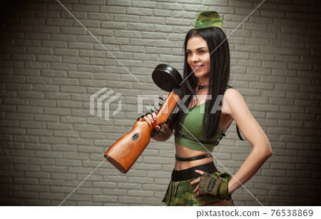 A woman in a sexy military uniform with a World War II PPSH-41 submachine gun is dressed in a short skirt and leather belts A woman in a sexy military uniform with a World War II PPSH-41 submachine gun is dressed in a short skirt and leather belts 76538869