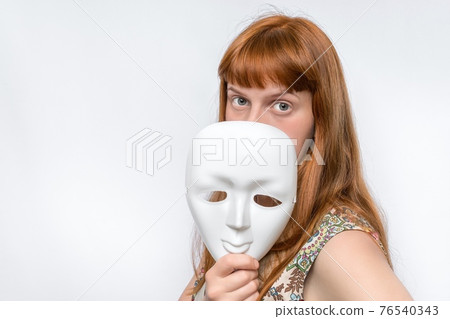 Mysterious woman cover her face behind anonymous mask Mysterious woman cover her face behind anonymous mask 76540343