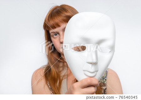 Mysterious woman cover her face behind anonymous mask Mysterious woman cover her face behind anonymous mask 76540345