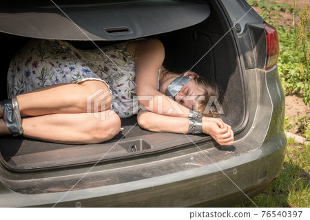 Woman with tied hands inside car trunk - kidnapping 76540397