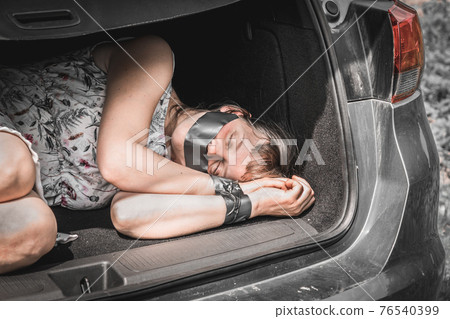 Woman with tied hands inside car trunk - kidnapping 76540399