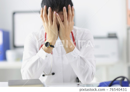 Tired doctor at his desk in medical office Tired doctor at his desk in medical office 76540431