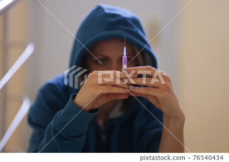 Woman drug addict sits on stairs with syringe Woman drug addict sits on stairs with syringe 76540434