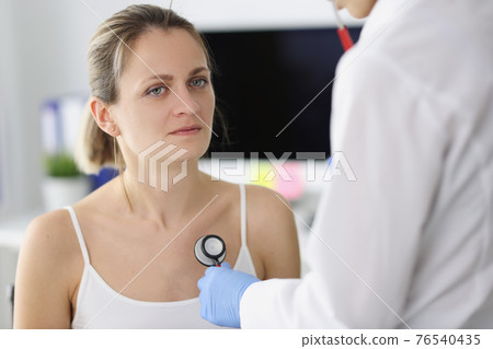 Patient listens to patient lungs through stethoscope Patient listens to patient lungs through stethoscope 76540435