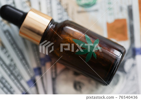 Bottle of marijuana oil lies on banknotes Bottle of marijuana oil lies on banknotes 76540436