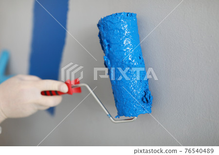 Master paints wall blue with paint roller 76540489