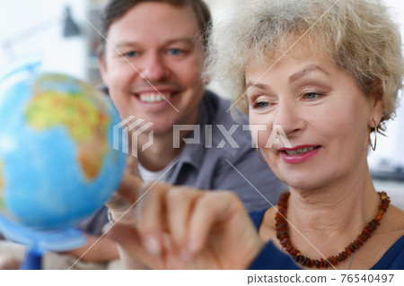 Elderly woman with her son is looking at globe Elderly woman with her son is looking at globe 76540497